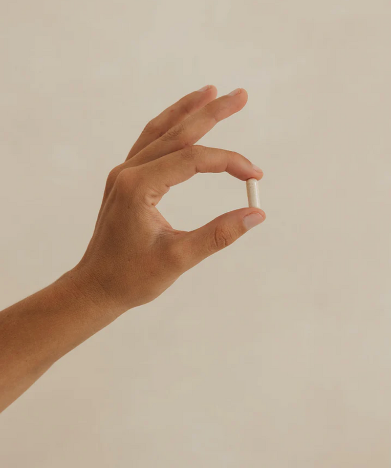Mano femenina sujetando un suplemento de SANA Nutrients 