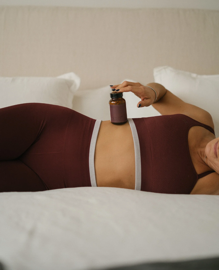 Mujer descansando con suplemento natural sobre el abdomen, relacionado con apoyo al ciclo menstrual