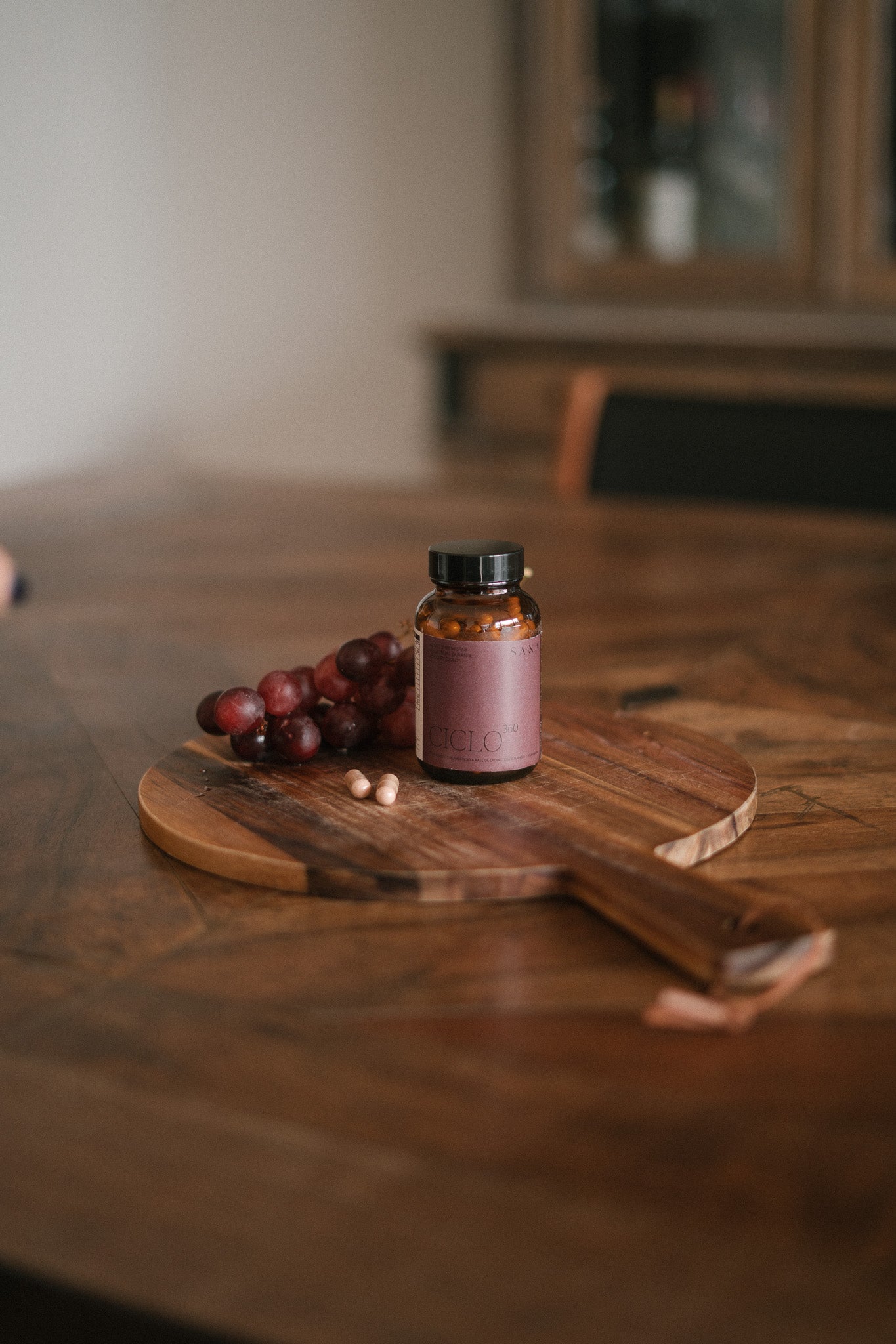 Ciclo 360 de SANA en mesa de madera con cápsulas, suplemento natural para el ciclo menstrual y bienestar femenino