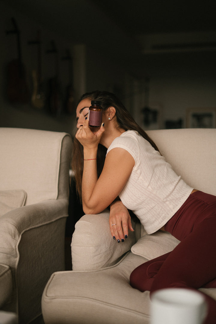 Mujer sosteniendo Ciclo 360 de SANA en casa, suplemento natural para el ciclo menstrual y bienestar femenino